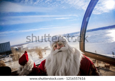 Jolly Santa Claus on the Ferris wheel in the open air against the sky