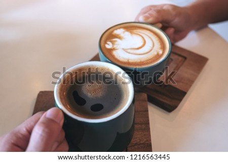 Close up image of a man and a woman clinking green coffee mugs in cafe