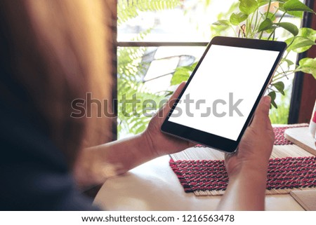 Mockup image of a woman holding black tablet pc with blank white desktop screen with green nature background