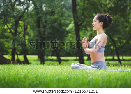 Fitness asian woman doing yoga exercise and relax with sportswear in green park at summer, healthy lifestyle concept