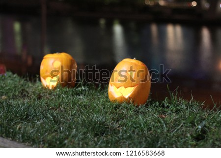 Halloween Pumpkins head. Orange pumpkin with a smile and eyes on night city and lights background.