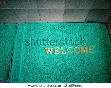 green mat placed in a doorway, welcome, on which people can wipe their shoes on entering a building