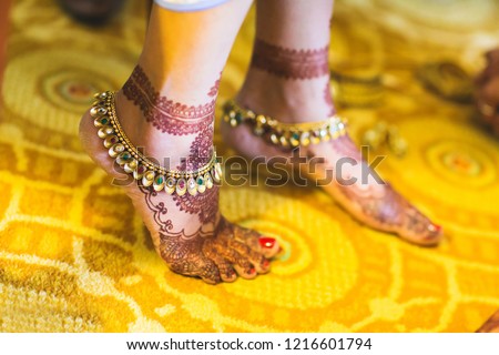 Indian bridal wearing gold payal anklets and showing foot mehndi design Royalty-Free Stock Photo #1216601794
