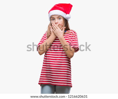 Young beautiful girl wearing christmas hat over isolated background shocked covering mouth with hands for mistake. Secret concept.