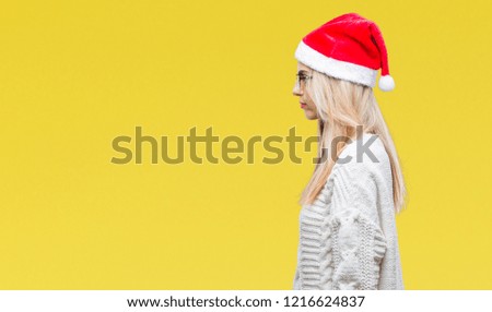 Young beautiful blonde woman wearing christmas hat over isolated background looking to side, relax profile pose with natural face with confident smile.