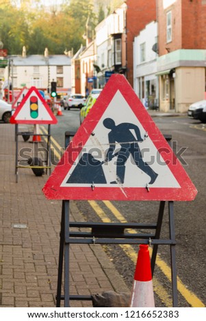 Temporary road works signs and traffic lights controlling vehicle access during highway repairs on a typical British urban street