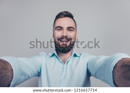 Close up studio photo portrait of glad excited cheerful good mood attractive nice guy holding camera with two hands looking at you make take selfie isolated grey background