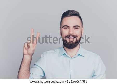 Close up studio photo portrait of handsome calm peaceful attractive with brown bristle stubble excited good he him human with toothy beaming grinning smile make give v-sign isolated grey background