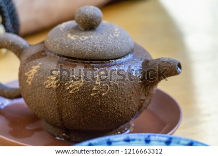 Puerh tea drinking in a traditional style on a wooden table. Antique tea-ware and figurines near tea bricks.