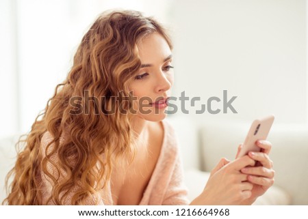 Close up photo of cheerful charming careless carefree tender lady in sweater with her modern hairdo she sit on comfort sofa or couch indoor nice idyllic interior room look on gadget screen