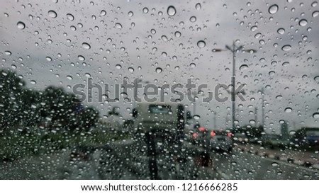 Road view through car window with rain drops, blur. 