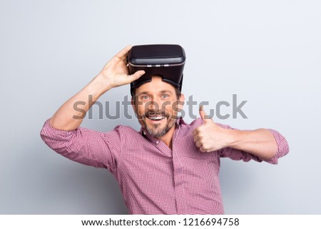 Portrait of cheerful glad positive attractive person in checkered casual wear with virtual glasses on head look at camera demonstrate ok okay thumb up isolated on light gray background