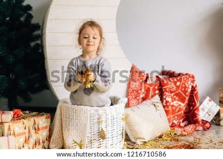 A little pretty girl with modern clothes stands on the background of the moon and the basket is decorated with new year