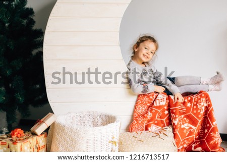 A little pretty girl with modern clothes stands on the background of the moon and the basket is decorated with new year
