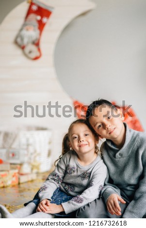 Little girl and boy sitting on the background of the moon and the baskets decorated under the new Year