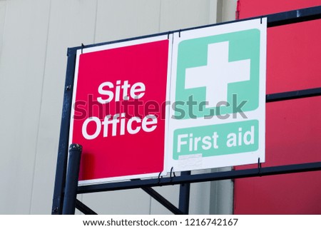First aid site office sign on construction building door railing for workplace health and safety green cross