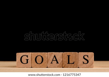 Goals, Wood block cube on wooden table isolated on black background with word GOALS, conceptual