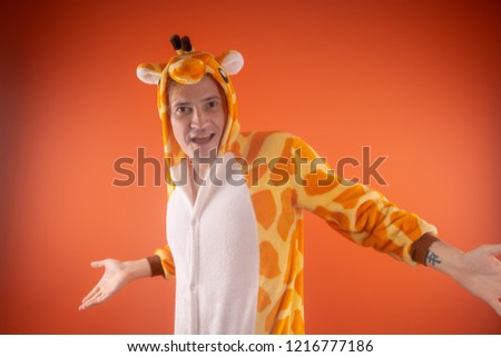 pajamas in the form of a giraffe. emotional portrait of a guy on an orange background. crazy and funny man in a suit. animator for children's parties
