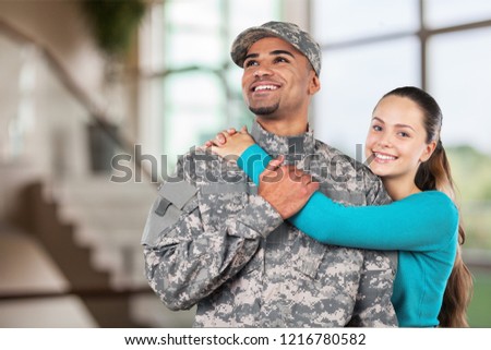 Smiling soldier with his wife standing against