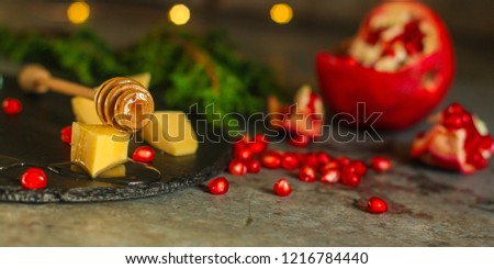pomegranate grain, cheese and honey - appetizer on a slate plate on a wooden background. top view.
