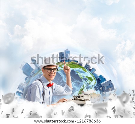 Handsome man writer in hat and eyeglasses pointing up while using typing machine at the table with flying letters and Earth globe among cloudy skyscape on background. Elements of this image furnished
