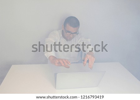 Young handsome man with mobile phone and laptop computer. White background. Emotional face with expression. Smoke in room.