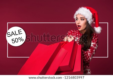 Beauty model girl in santa hat on red background. Funny laughing surprised woman portrait. Open mouth. True emotions. Shopping and sale. Shopaholic girl. Black Friday, holiday celebration.