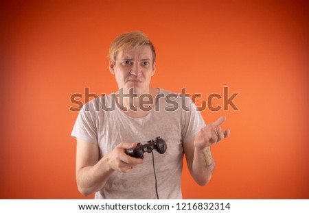 a young guy holding a gamepad in his hands. emotional portrait. man playing computer games. Concept: emotional gamer
