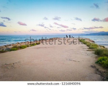 A photo of the sand and rocks and the gorgeous sunset in Punta Negra, located between between Cap Blanc and Racó beach in Cullera, a touristic town by the Mediterranean Sea in Valencia, Spain, Europe.