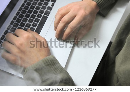 Man hands and fingers on laptop computer. Smoke in room.