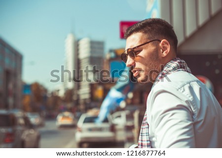 Stylish businessman is walking down the street in an urban city, looking in the beautiful buildings around him