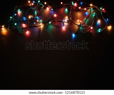 Christmas background with lights and free text space. Christmas lights border. Glowing colorful Christmas lights on black background. New Year. Christmas. Decor. Garland.