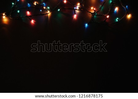 Christmas background with lights and free text space. Christmas lights border. Glowing colorful Christmas lights on black background. New Year. Christmas. Decor. Garland. Royalty-Free Stock Photo #1216878175