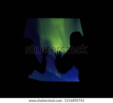 Couple watches the northern lights from the bedroom window. Woman and man at winter night.