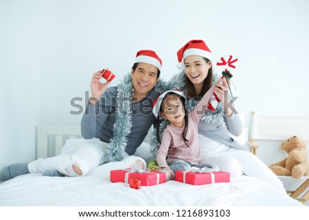 Asian family celebrating Christmas wearing red Santa Claus hat with decorative gifts and gift boxes or present in bedroom, holiday in festive Merry Christmas or X'mas and happy new year concept Royalty-Free Stock Photo #1216893103