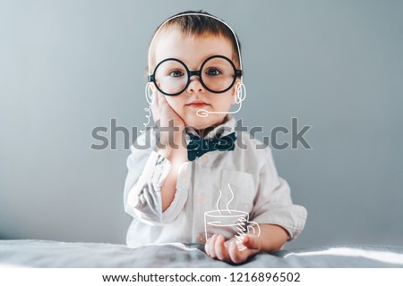 Cute little genius. Baby boy wearing smart outfit and eye glasses working as call center operator answering several people and drinking imaginery coffee. Children and technologies concept. 