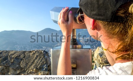 Young Girl - traveler, looking through telescope,  panoramic viewing of Alanya city and beaches from the viewpoint of the mountain: "Alanya Kalesi". Toned picture, Copy space for your design