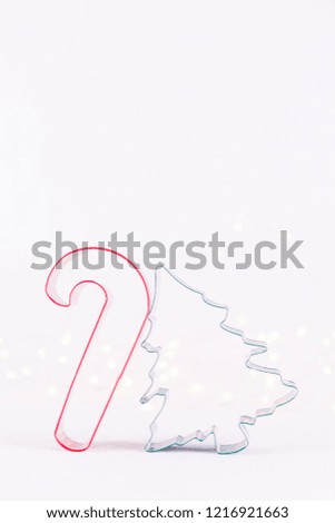 Candy cane and Christmas tree cookie cutters on white sparkling background with bokeh lights. Holiday Christmas and New Year background. Vertical
