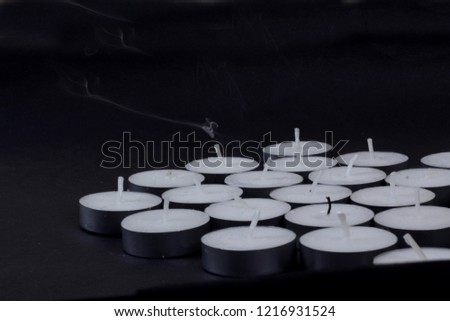 Typical aluminium burning tea candle isolated on white background with shadow reflection. Tea candle with flame and black wick. Tea candle with burning ingle and burned candlewick. Macro photography
