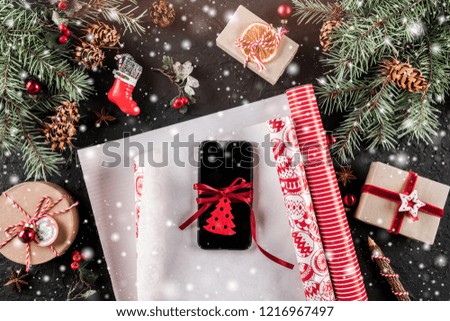 Christmas composition with mobile phone, xmas wrapping, Fir branches, gifts, red decorations on dark background. Xmas and Happy New Year card, bokeh, sparking, glowing. Flat lay, top view