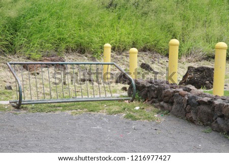 Bike Rack, Yellow Poles and Rock Wall In Parking Lot with Grassy Hill