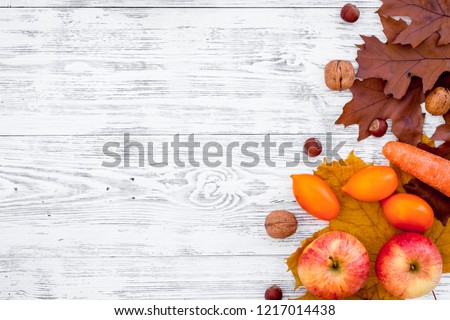 Autumn nature concept. Background with autumn symbols. Brown leaves, apple, tomatoes on white wooden background top view copy space