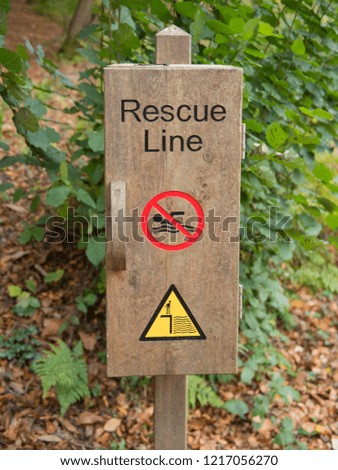 Wooden Box with a Rescue Line and Warning Signs for "No Swimming" and "Deep Water" by the Side of a Lake in Rural West Sussex, England, UK