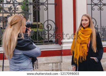 Girl photographer takes a photo of a blonde on the streets of Moscow. Two blondes with long hair on a street photo shoot.