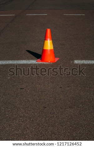 Striped orange cone on the asphalt road.