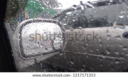 water drops on glass side mirror of car closeup rainy day view from window