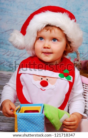 portrait of cute baby girl in red santa hat playing with toys
