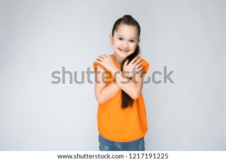 Girl on a gray background folded her hands at his chest.