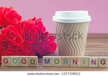 Paper cup with coffee and red roses on a wooden background, inscription "Good morning" (concept)