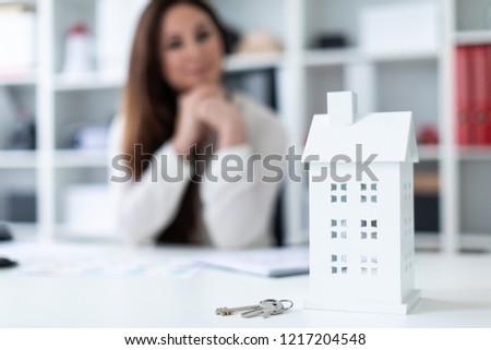 A young girl sitting at the table. Photo with depth of field, highlighted focus on home and keys.
